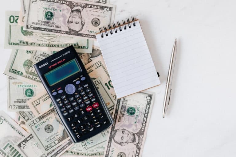 Calculator and notepad on a stack of paper bills